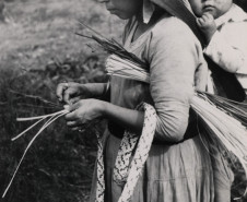Mulher Kaingang carregando o filho nas costas enquanto confecciona um chapéu de taquar. Terra Indígena Ivaí - Municípios de Manoel Ribas e Pitanga, PR.