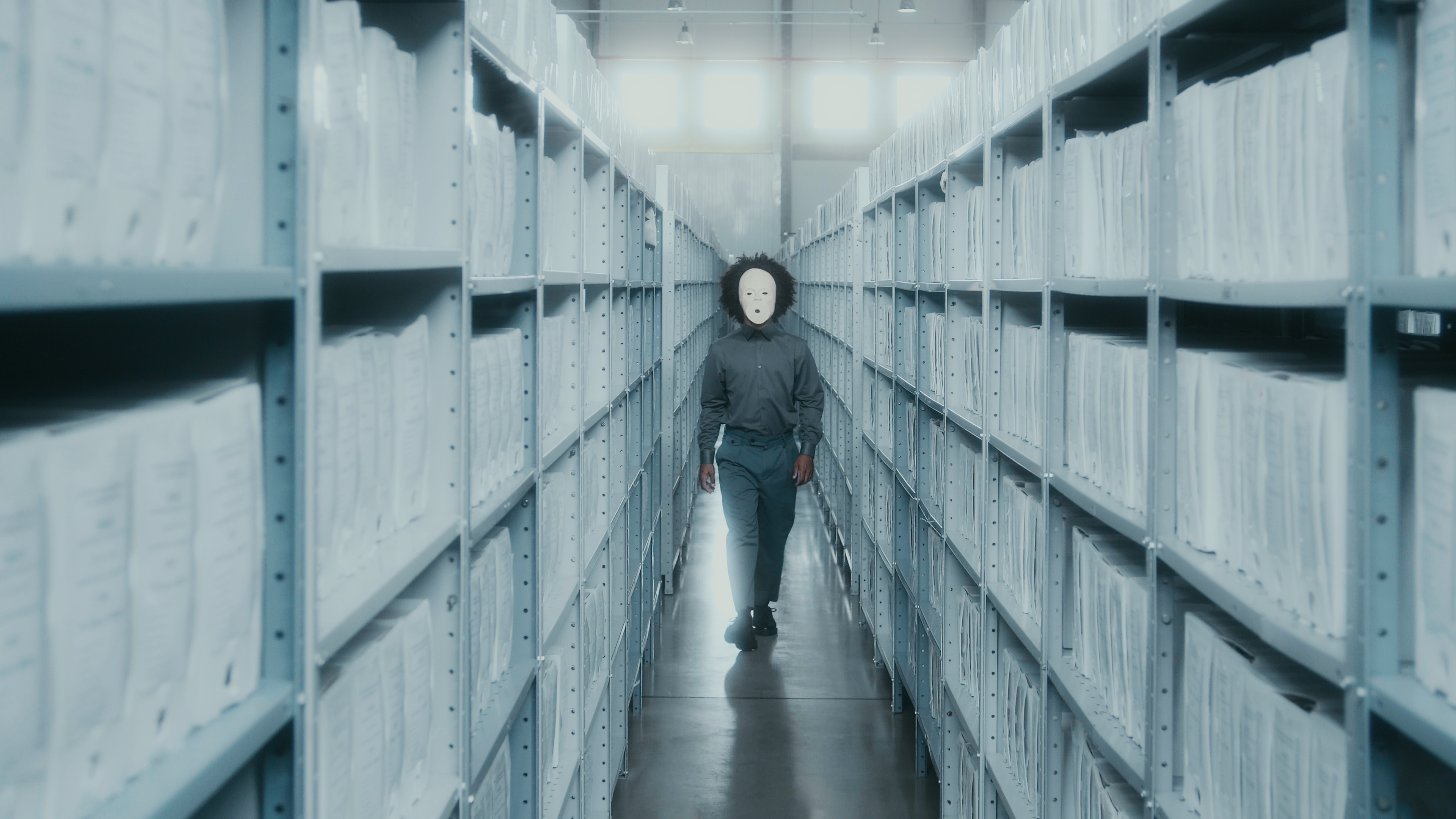 homem negro com uma máscara branca de cerâmica coreografando em um arquivo