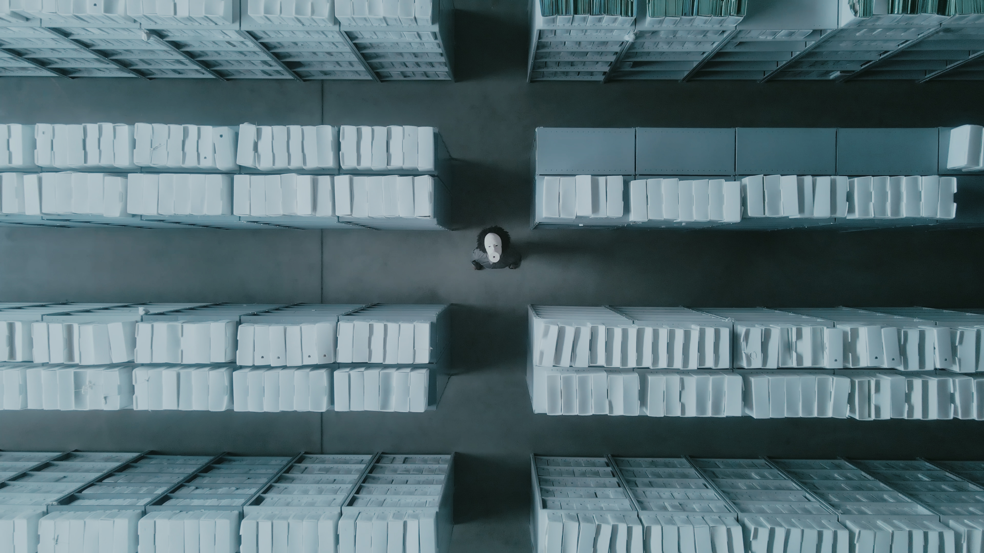 homem negro com uma máscara branca de cerâmica coreografando em um arquivo