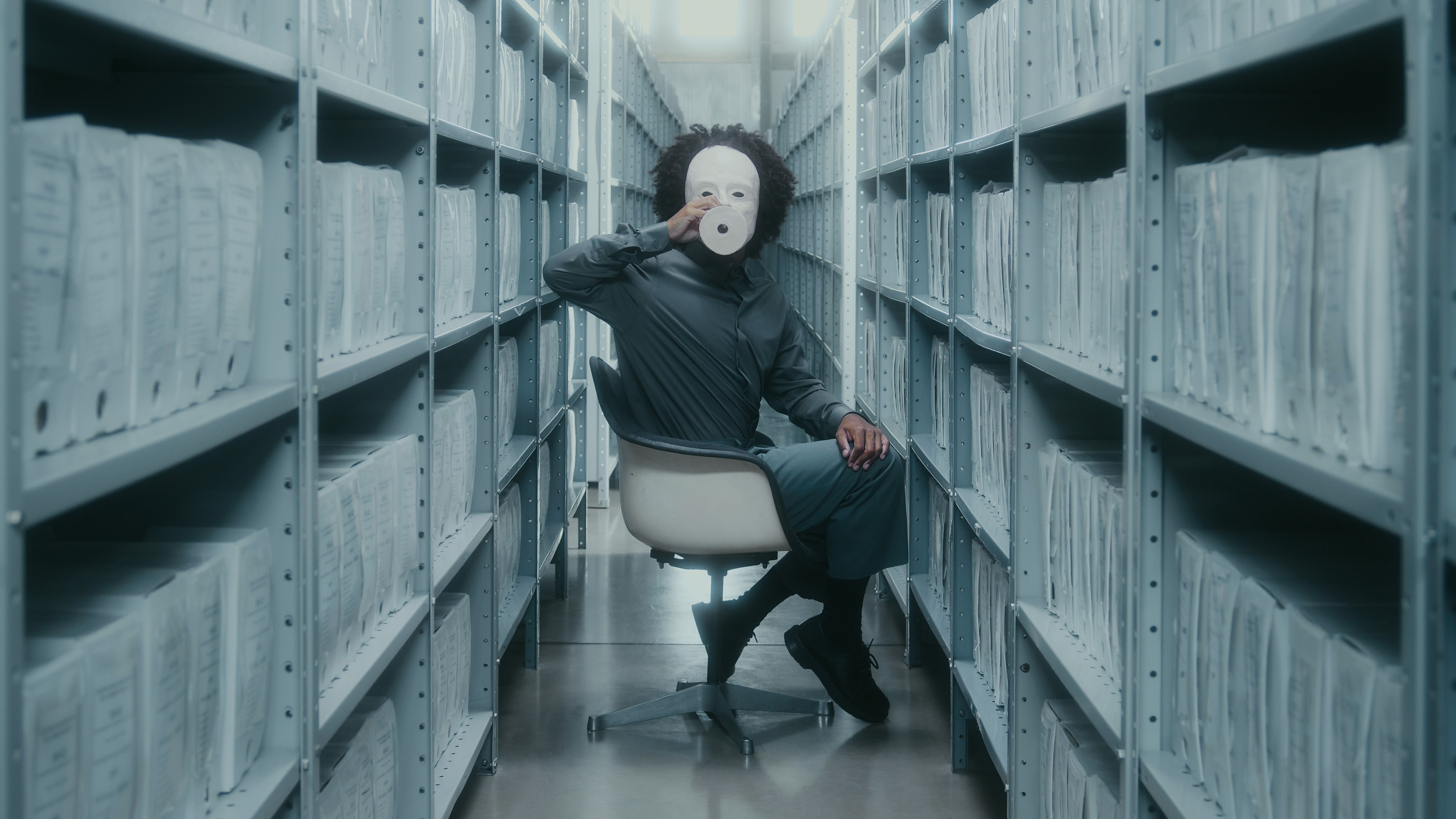 homem negro com uma máscara branca de cerâmica coreografando em um arquivo