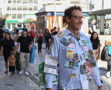 Cena da performance Arte Panfletária, onde aparece o artista Elilson em meio ao centro urbano da cidade de Curitiba.