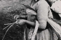 Mulher Kaingang carregando o filho nas costas enquanto confecciona um chapéu de taquar. Terra Indígena Ivaí - Municípios de Manoel Ribas e Pitanga, PR.