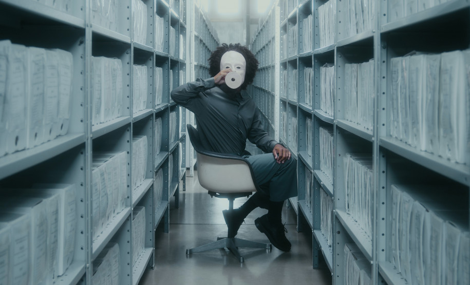 homem negro com uma máscara branca de cerâmica coreografando em um arquivo