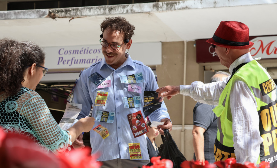 Cena da performance Arte Panfletária, onde aparece o artista Elilson em meio ao centro urbano da cidade de Curitiba.
